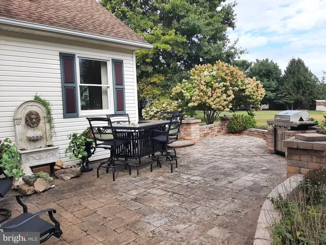 a view of a patio with table and chairs potted plants and a large tree