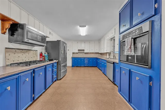a large kitchen with stainless steel appliances and wooden cabinets