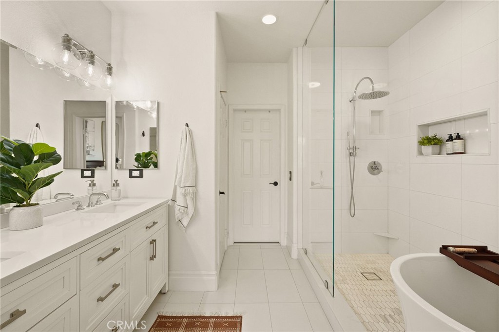 6807 Simmons Way Moorpark, CA 93021 - Photo 19 of 43 a bathroom with a double vanity sink a large mirror a shower and a bathtub