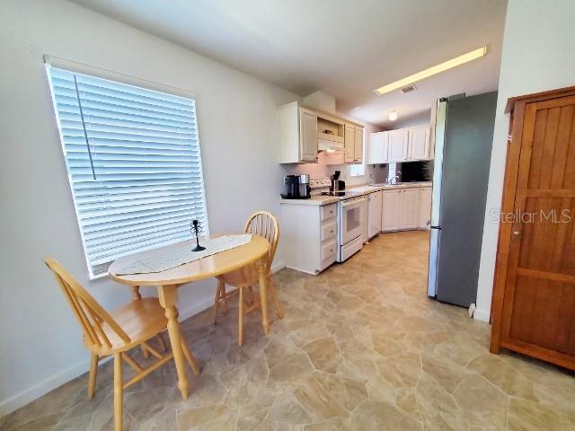 29200 South Jones Loop Road, Unit 125 Punta Gorda, FL 33950 - Photo 43 of 52 a kitchen with a table chairs refrigerator and microwave