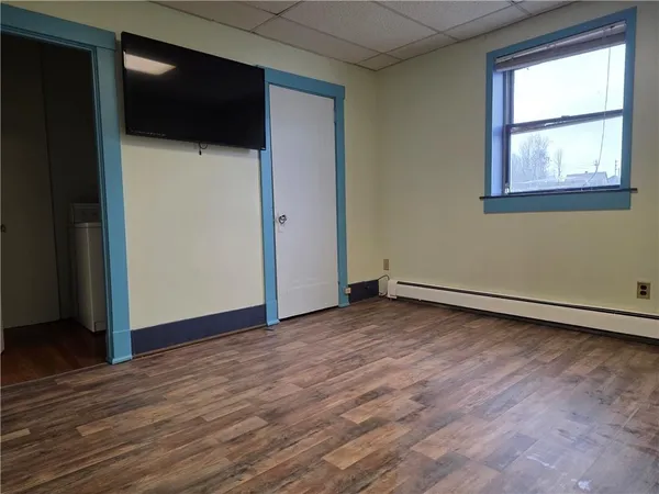 a view of an empty room with wooden floor and a window