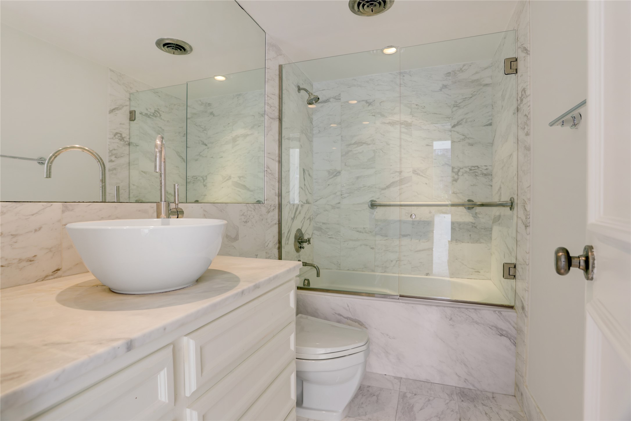 2701 Westheimer Road, Unit 2D Houston, TX 77098 - Photo 15 of 48 The bathroom is finished in classic marble, featuring a custom vanity with vessel sink, glass-enclosed tub and shower, and clean, understated fixtures.