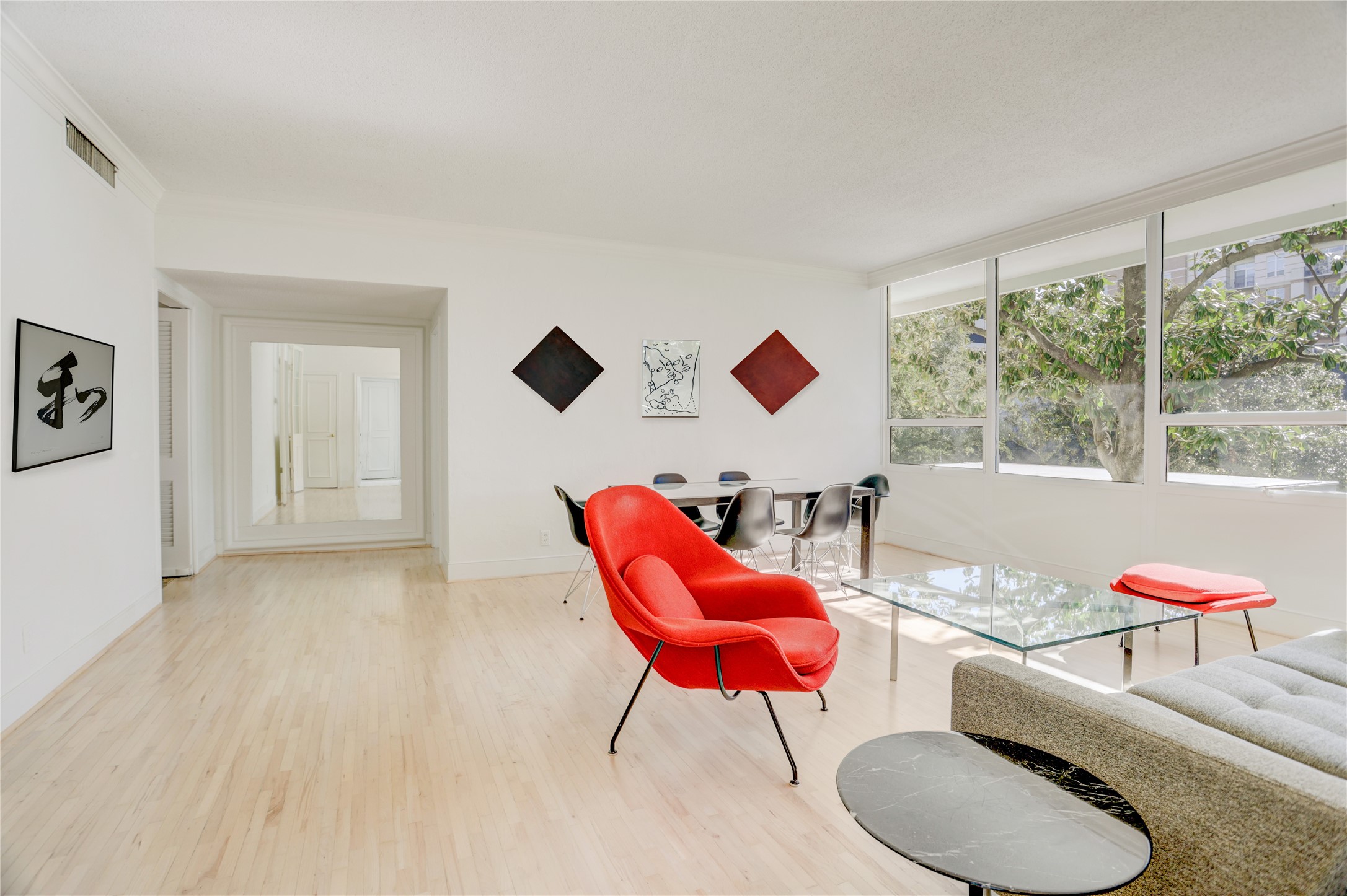 2701 Westheimer Road, Unit 2D Houston, TX 77098 - Photo 16 of 48 From the living room, the sightline extends toward the library and kitchen, anchored by a large mirror that adds visual depth to the hallway.