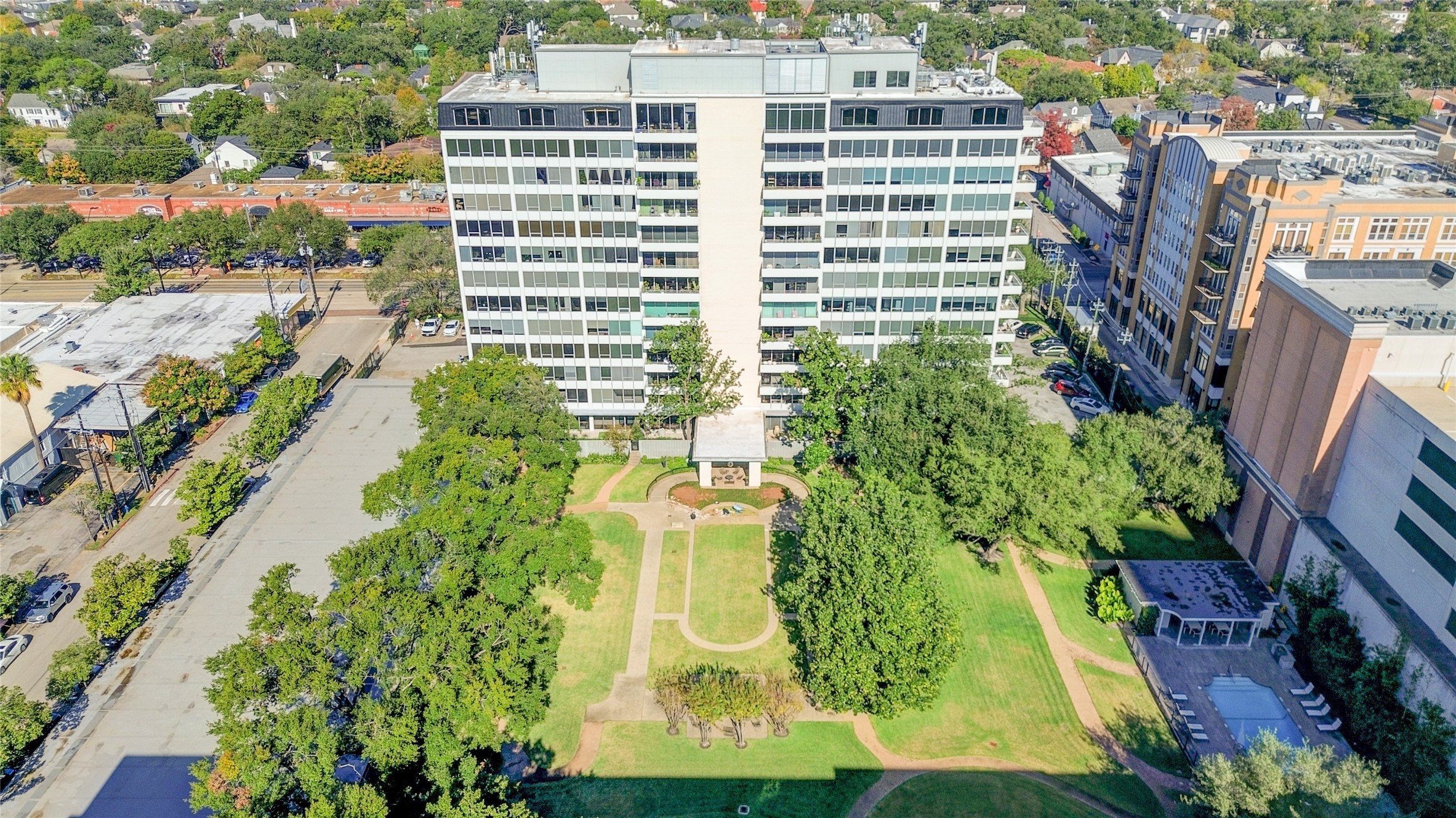 2701 Westheimer Road, Unit 2D Houston, TX 77098 - Photo 33 of 48 This view highlights the building’s expansive two-acre private park, with mature landscaping, open green space for gatherings or quiet enjoyment, and the pool visible to the right.