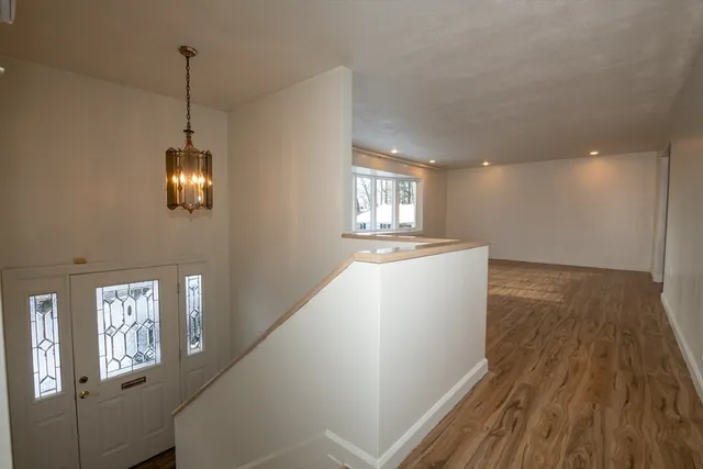 a view of an empty room with wooden floor and windows