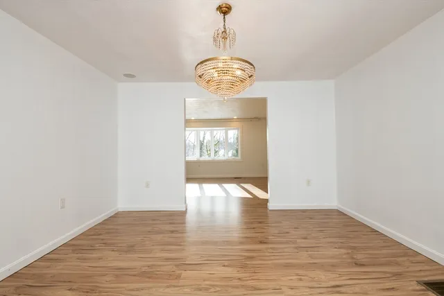 a view of an empty room with wooden floor and window