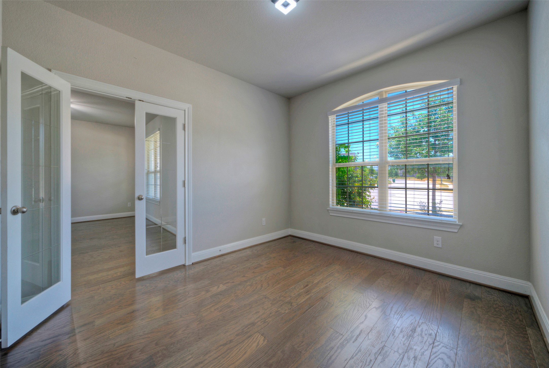 2260 Hat Bender Loop Round Rock, TX 78664 - Photo 9 of 40 Natural light floods through an arched window, illuminating the rich hardwood floors and French doors in this inviting space.
