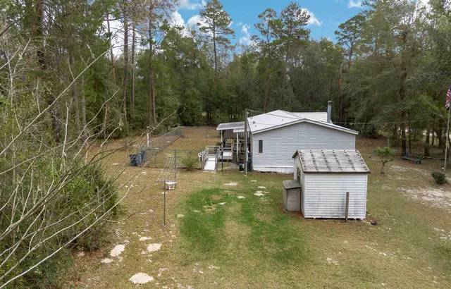 a view of a wooden house with a big yard and large trees