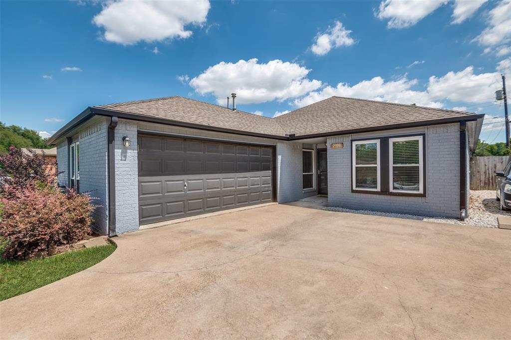 Single story home featuring brick siding, a garage, driveway, and roof with shingles