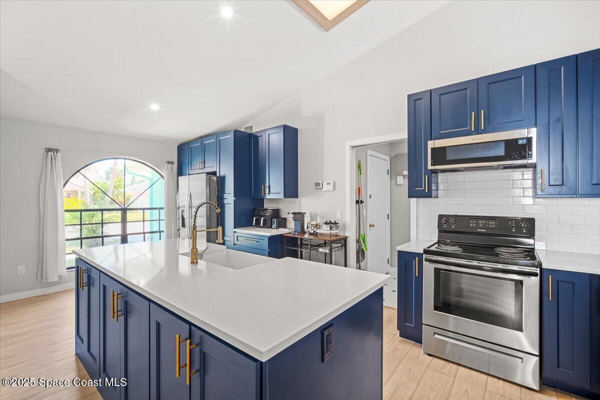 1709 Palm Ridge Road Melbourne, FL 32935 - Photo 11 of 43 a kitchen with kitchen island granite countertop wooden cabinets stainless steel appliances and a large window
