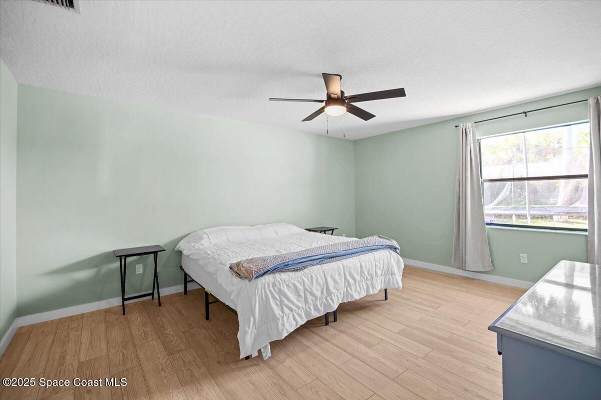 1709 Palm Ridge Road Melbourne, FL 32935 - Photo 24 of 43 a bedroom with a bed and wooden floor