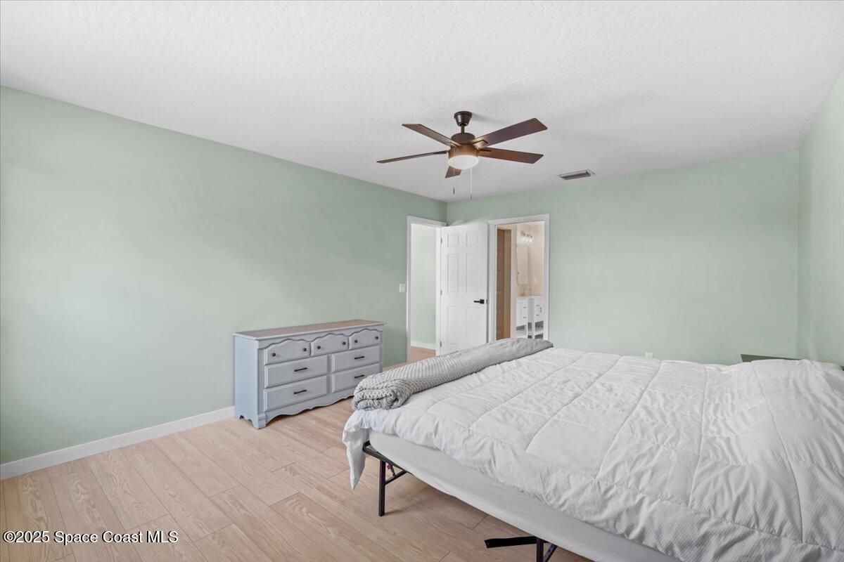 1709 Palm Ridge Road Melbourne, FL 32935 - Photo 25 of 43 a bedroom with a bed and a chandelier