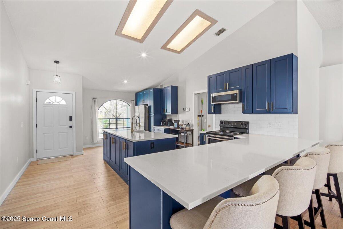1709 Palm Ridge Road Melbourne, FL 32935 - Photo 7 of 43 a kitchen with stainless steel appliances granite countertop a table chairs sink refrigerator and microwave