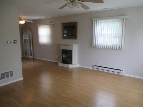 an empty room with wooden floor a ceiling fan and a fireplace