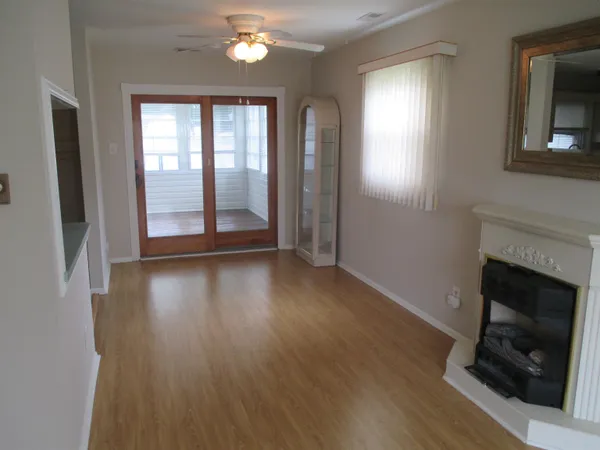 an empty room with wooden floor fireplace and windows