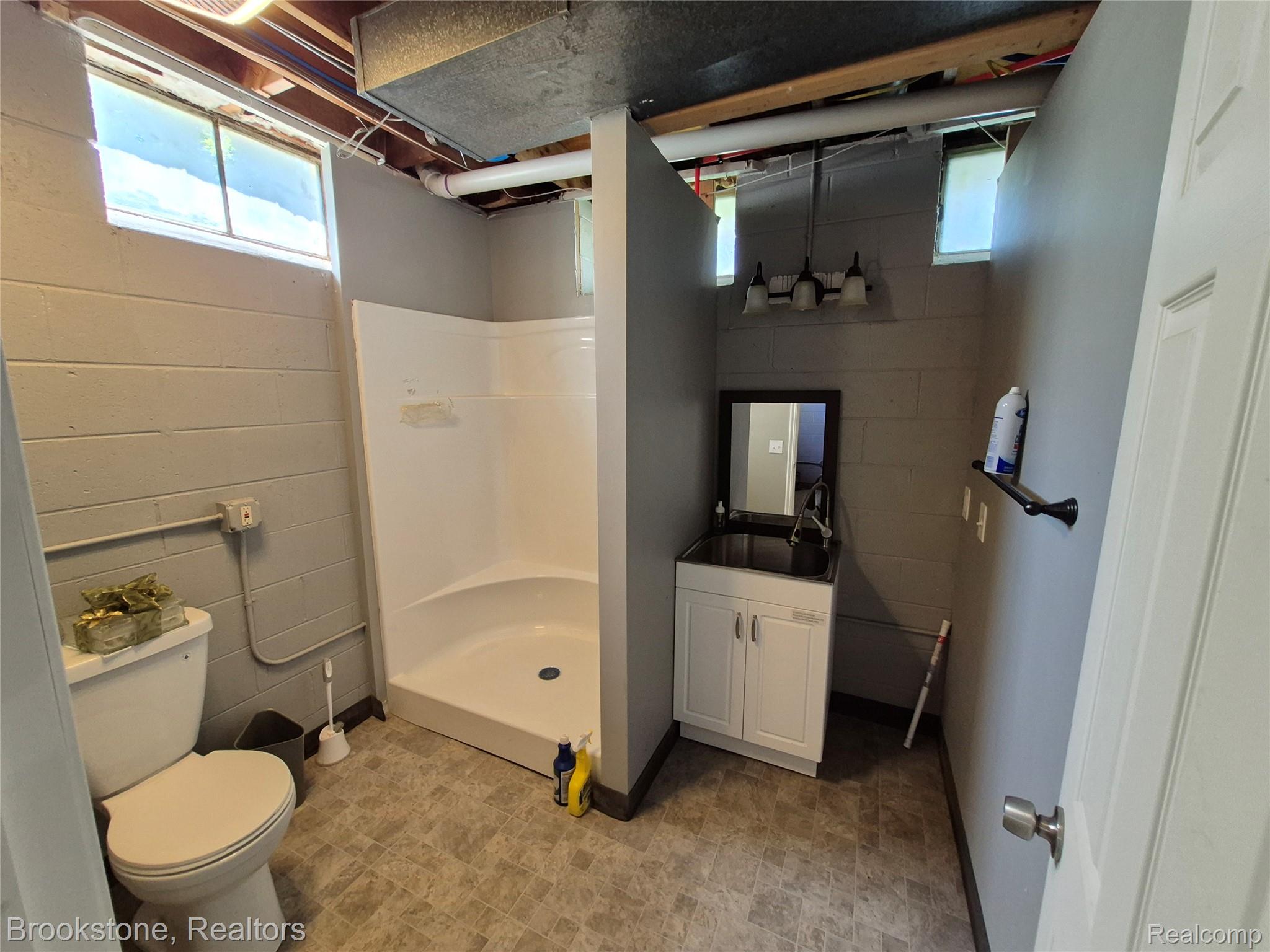 4295 Sashabaw Road Waterford, MI 48329 - Photo 32 of 37 Bathroom featuring a white shower stall, a white toilet, and a vanity with a dark countertop and white cabinetry