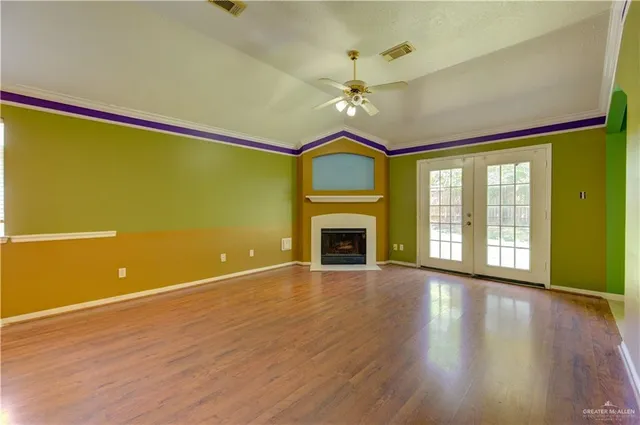 a view of an empty room with a window and wooden floor