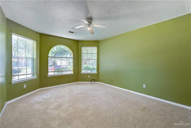 an empty room with windows and chandelier fan