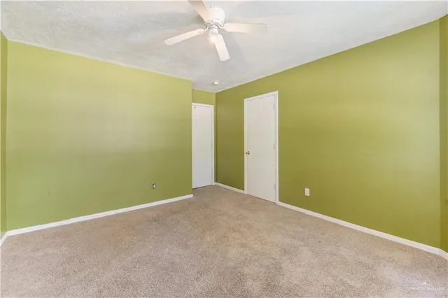 an empty room with a yellow ceiling fan and painted walls