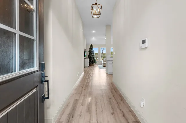 a view of a hallway with wooden floor and a bathroom
