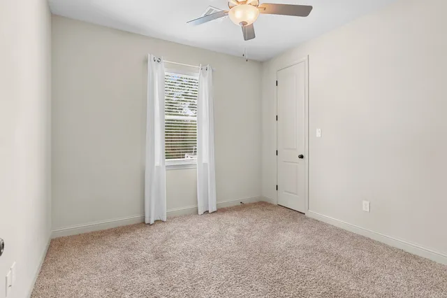 an empty room with a ceiling fan and window