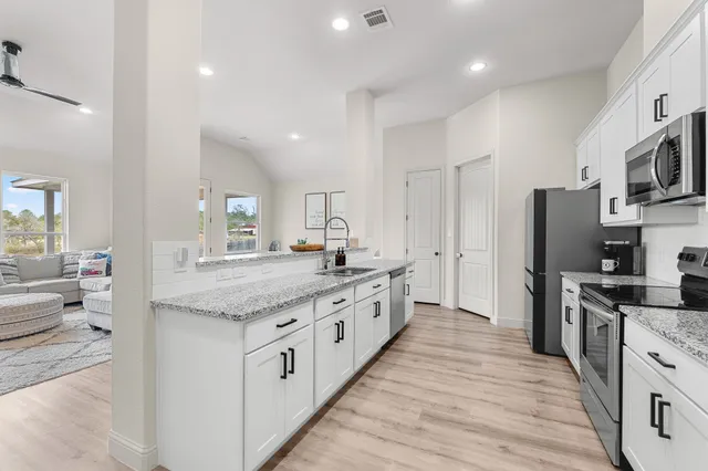 a large kitchen with stainless steel appliances kitchen island granite countertop a large counter top and wooden floors