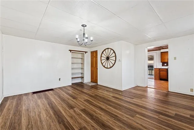 a view of an empty room with window and wooden floor
