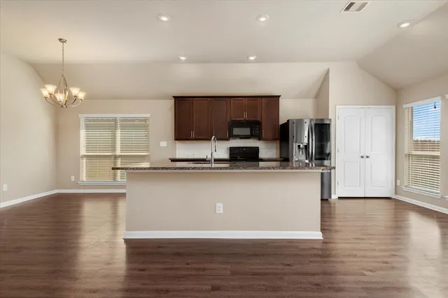 a living room with stainless steel appliances granite countertop a kitchen island a stove a sink a refrigerator and a view of kitchen