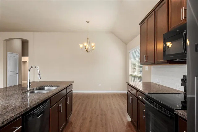 a kitchen with granite countertop a sink cabinets and wooden floor
