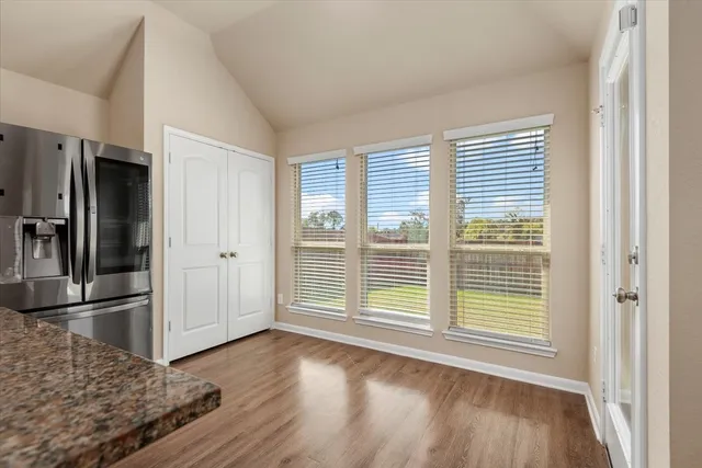 a view of a livingroom with wooden floor and kitchen space