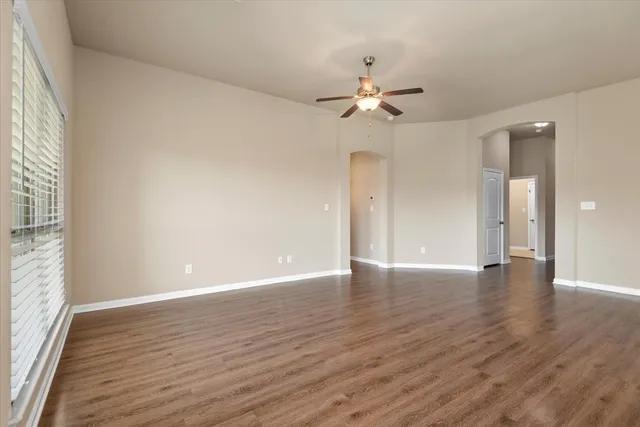 a view of an empty room with a window and wooden floor