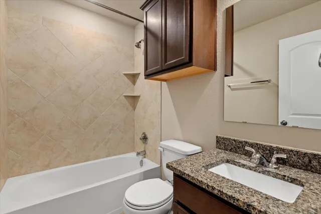a bathroom with a granite countertop sink toilet and shower