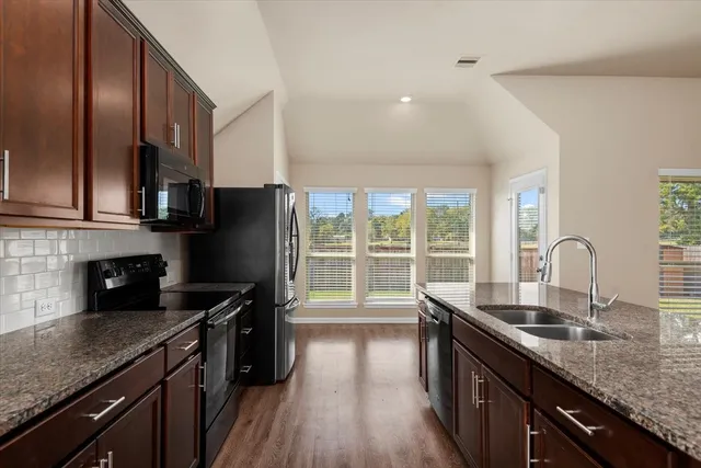 a kitchen with granite countertop a sink a counter space appliances and cabinets