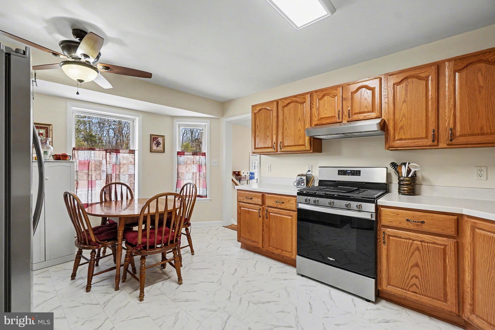8636 Winding Way Perry Hall, MD 21128 - Photo 8 of 40 a kitchen with stainless steel appliances granite countertop a stove top oven a sink dishwasher a dining table and chairs with wooden floor