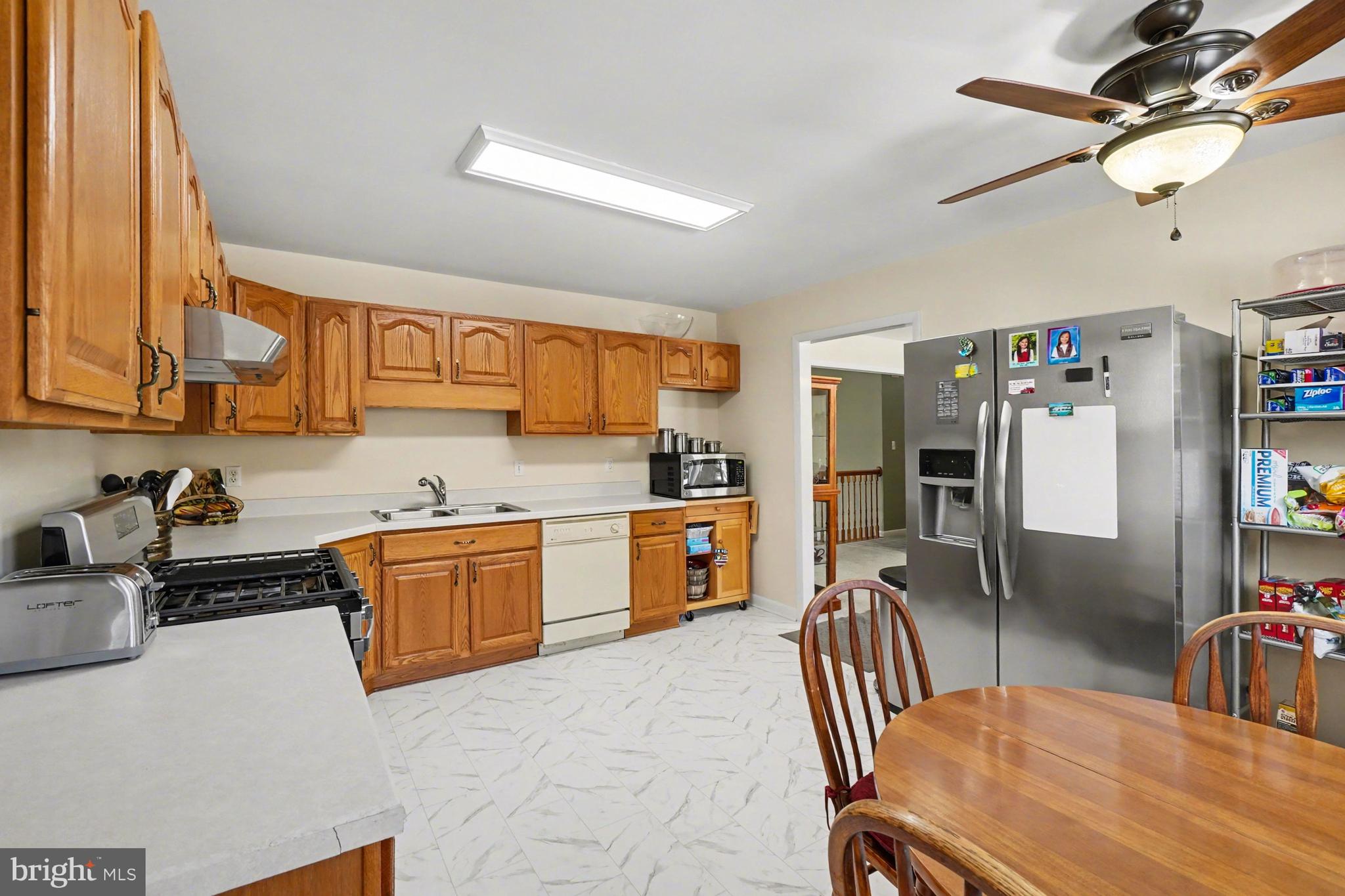 8636 Winding Way Perry Hall, MD 21128 - Photo 9 of 40 a large kitchen with stainless steel appliances granite countertop a sink a stove a dining table and chairs with wooden floor