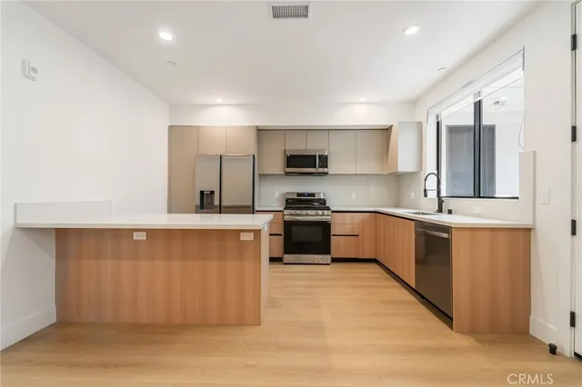 a large kitchen with stainless steel appliances wooden cabinets and a counter top space