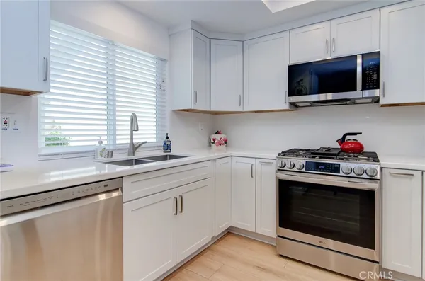 a kitchen with stainless steel appliances granite countertop white cabinets and a stove top oven