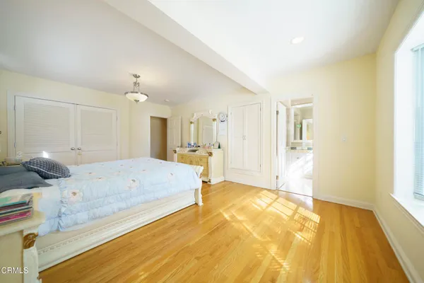 a spacious bedroom with a bed and wooden floor
