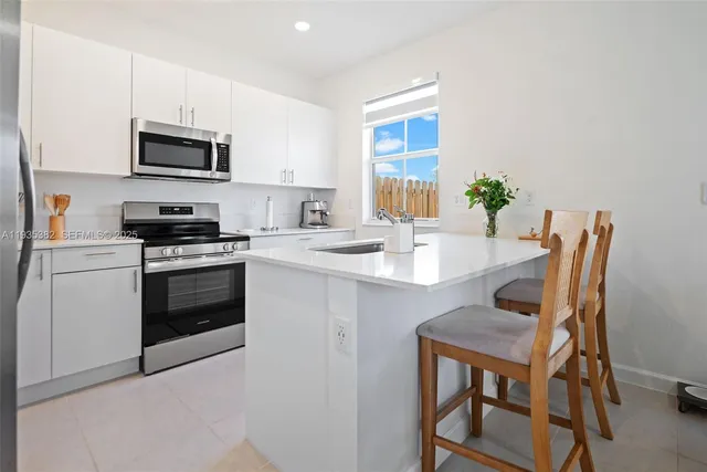 a kitchen with a stove a sink and chairs