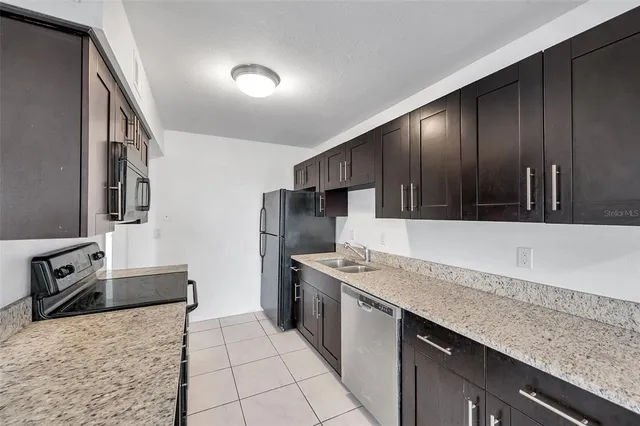 a kitchen with granite countertop a stove a sink and a refrigerator