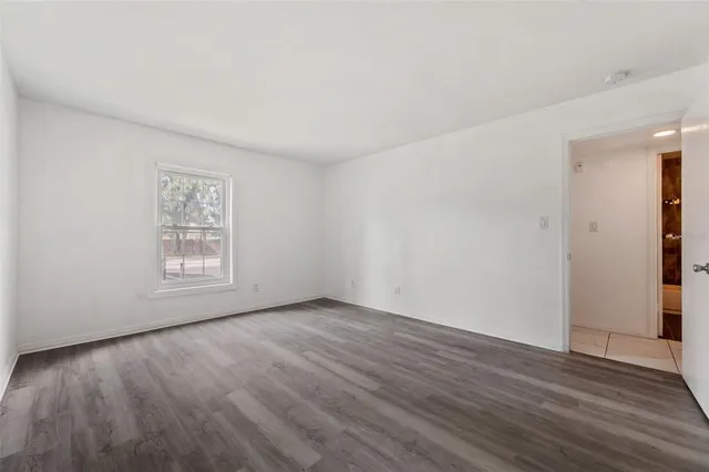 a view of an empty room with wooden floor and windows