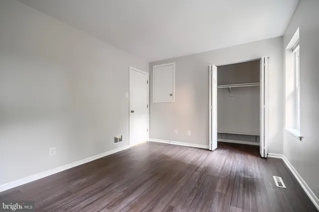 a view of an empty room with wooden floor and closet