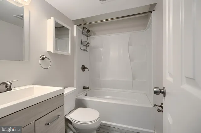 a bathroom with a bathtub shower sink vanity and toilet