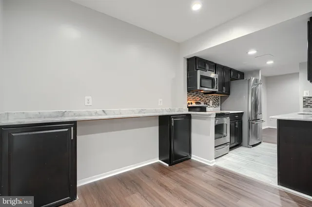 a kitchen with granite countertop a refrigerator and a stove top oven
