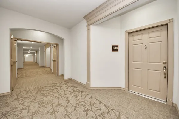 a view of an empty room with wooden floor and a kitchen