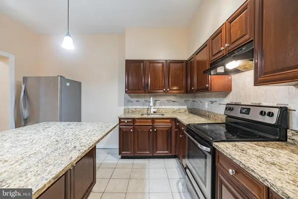 a kitchen with stainless steel appliances granite countertop wooden cabinets a stove a sink and a oven