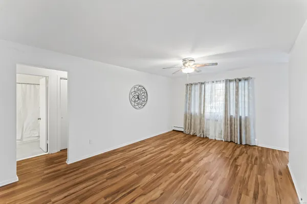 a view of an empty room with wooden floor and a window