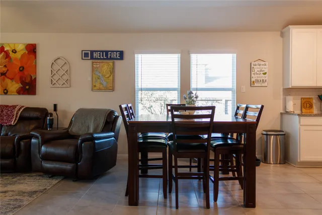 a living room with stainless steel appliances furniture a rug and a kitchen view