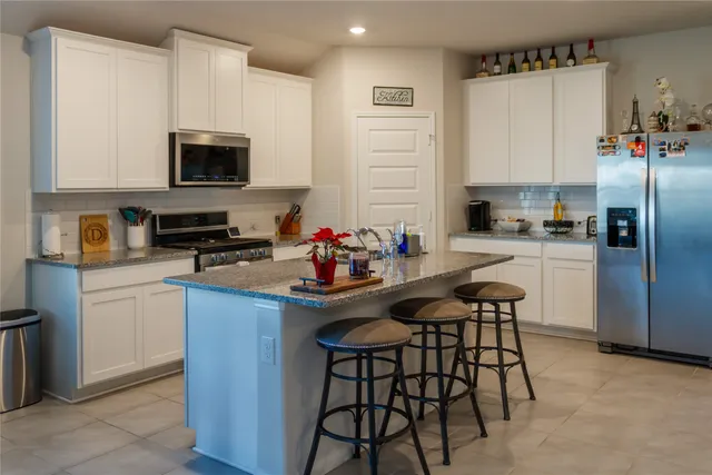 a kitchen with stainless steel appliances a sink a stove a microwave a refrigerator and cabinets