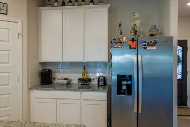 a kitchen with stainless steel appliances granite countertop a refrigerator a stove and white cabinets